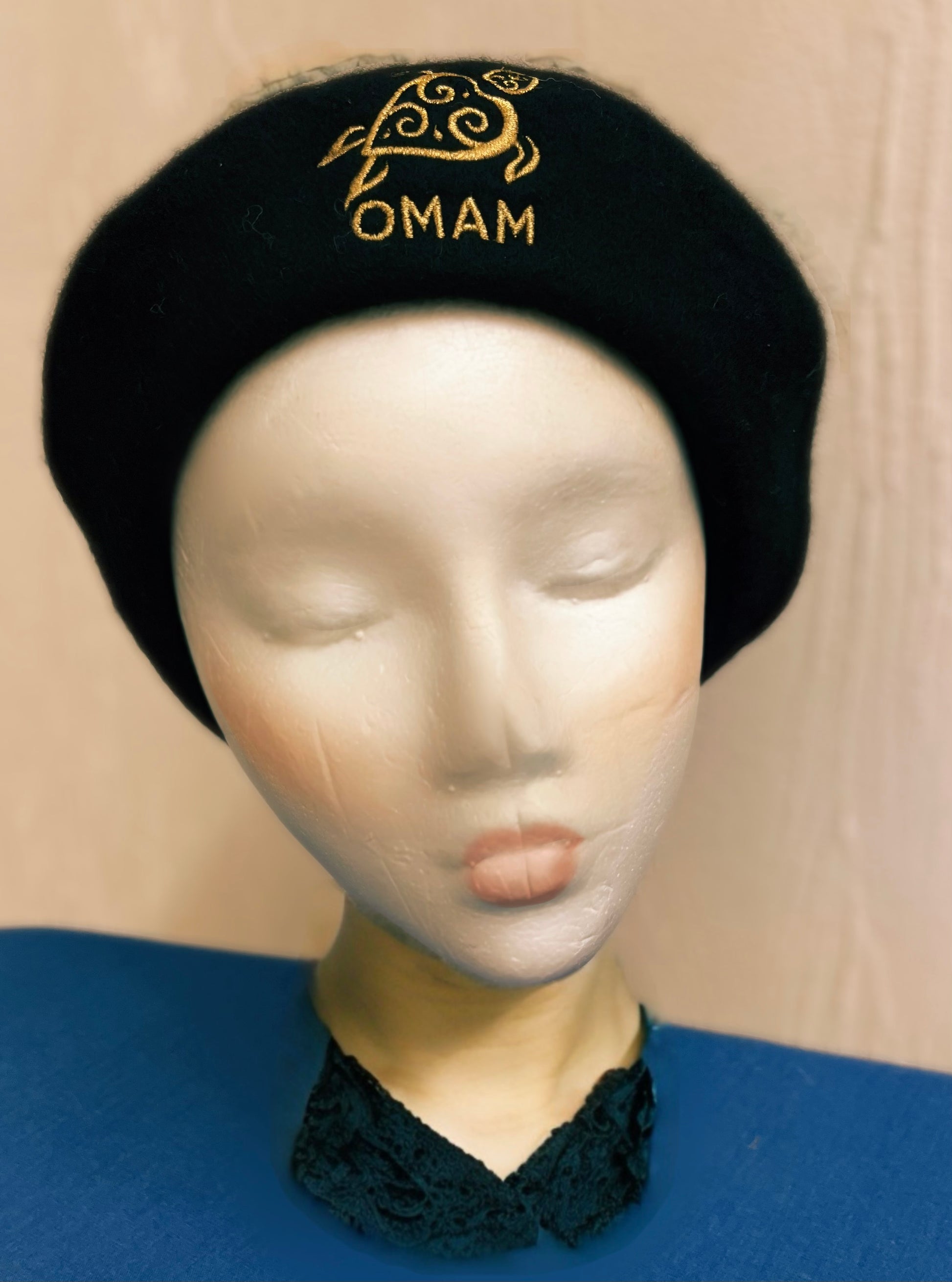 Black Beret with 'OMAM' Gold embroidered Turtle Logo on a mannequin head against a beige background