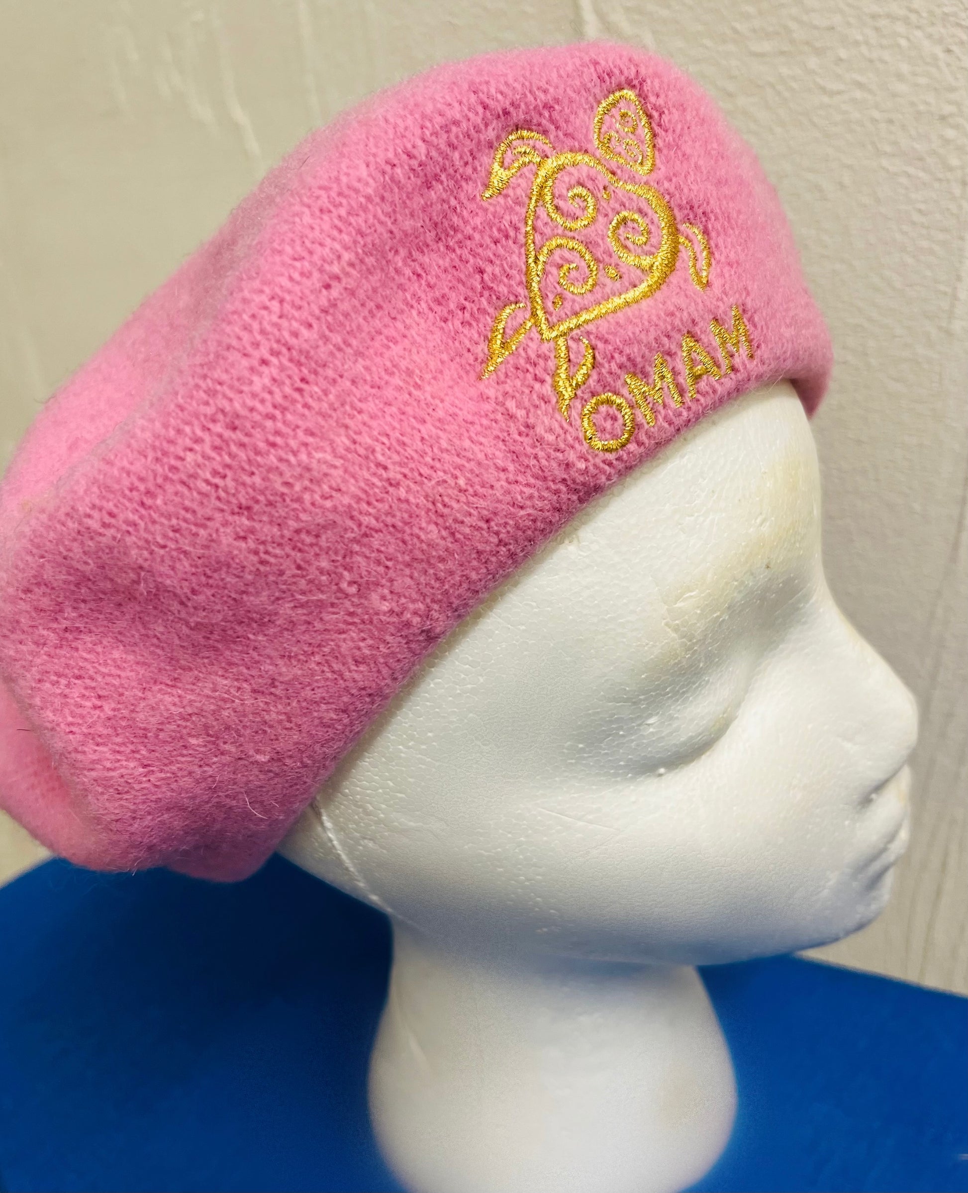 Pink BERET with gold embroidered OMAM Turtle logo design on a mannequin head.